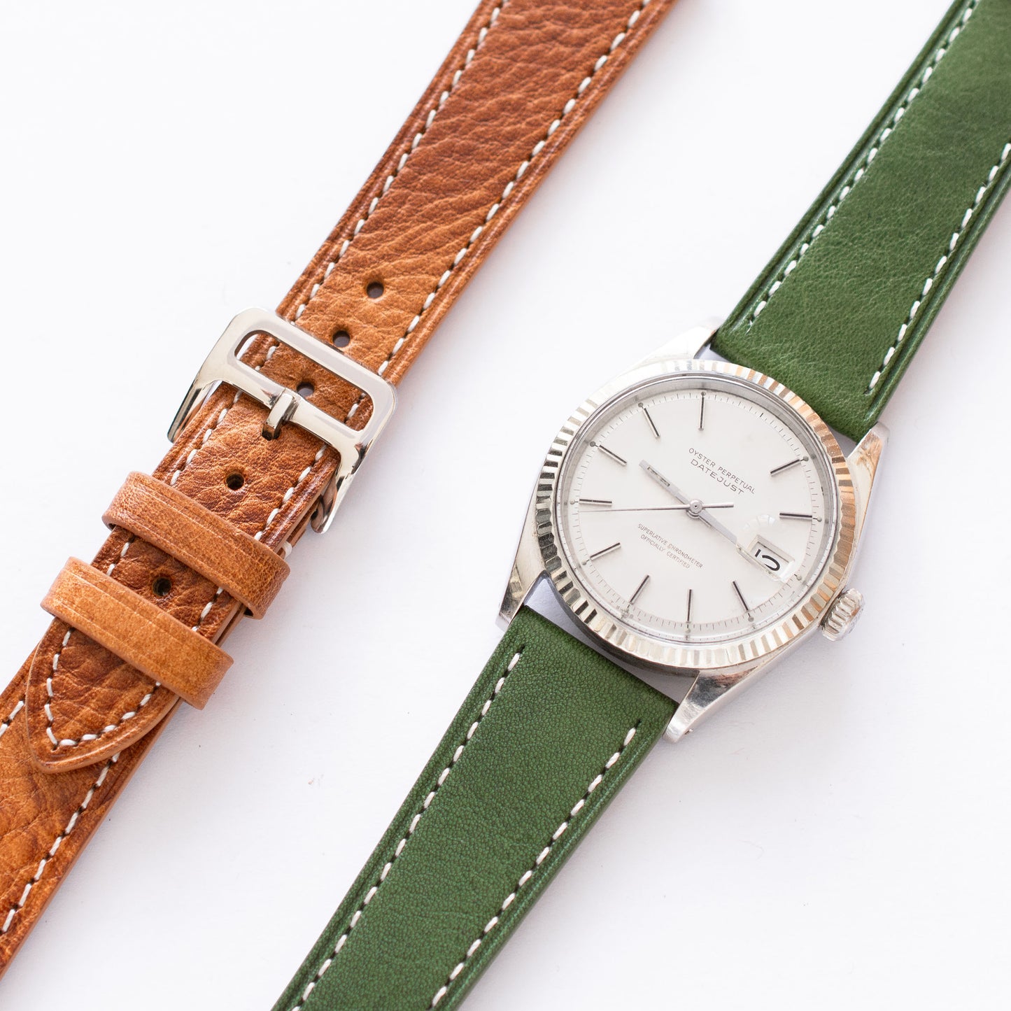 Two watches with brown and green leather straps on a white background watch buckle 